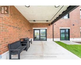 A brick building with a glass door entrance and a bench outside.