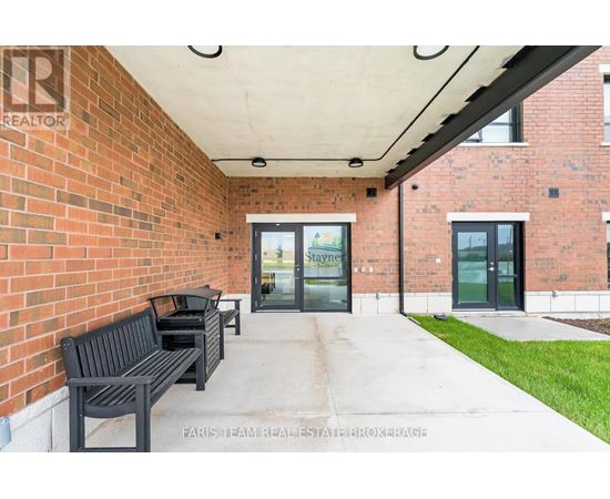 A brick building with a glass door entrance and a bench outside.