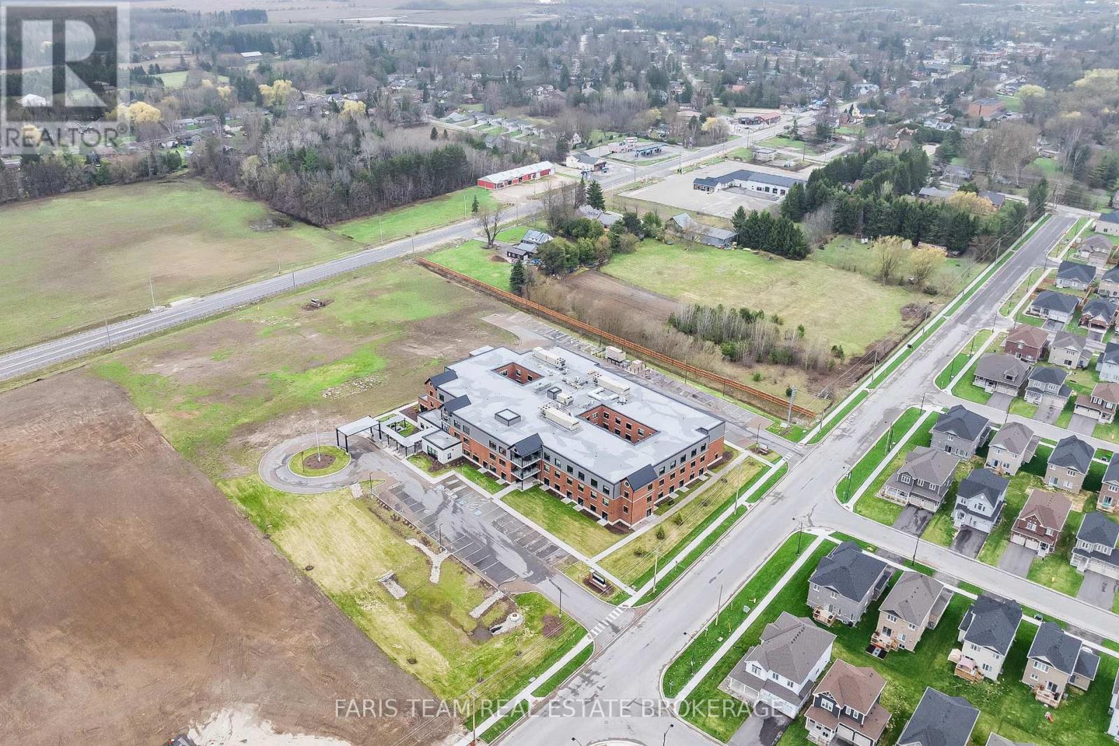 An aerial view of a real estate property with a large building and surrounding houses.