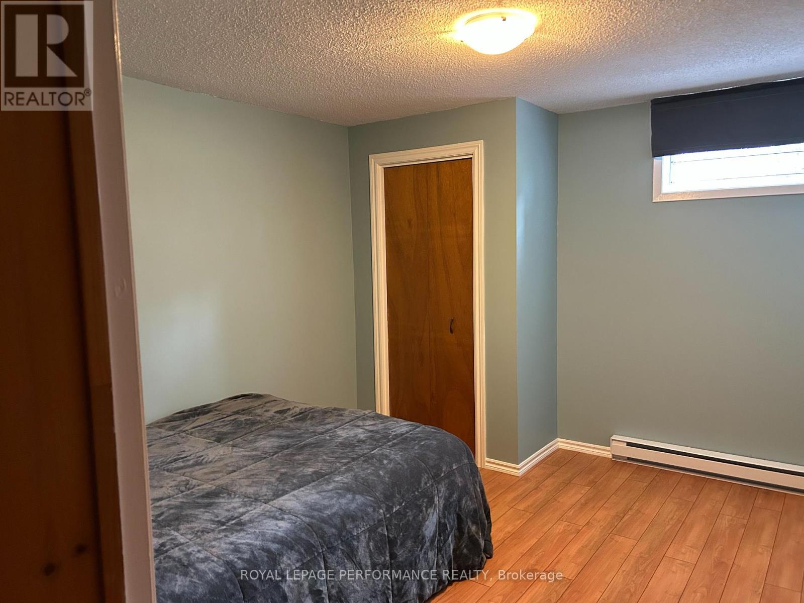 A bedroom with a bed, wooden door, and a window with blinds.