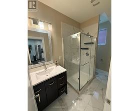 A bathroom with a sink, mirror, and shower.