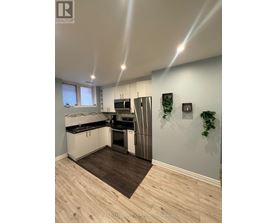 A modern kitchen with a wooden floor and white walls.