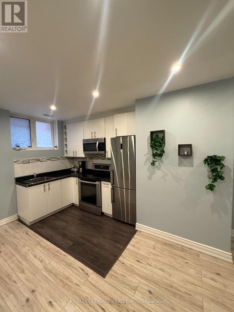 A modern kitchen with a wooden floor and white walls.