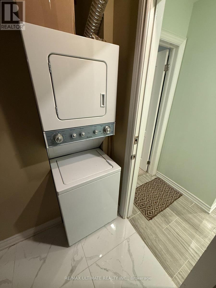 A white toilet with a silver tank and lid is in a bathroom with a brown rug on the floor.