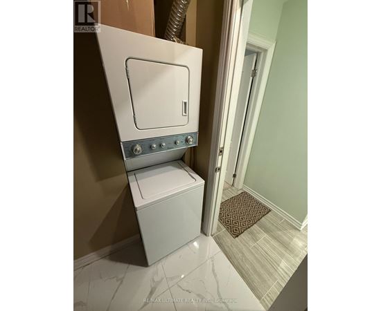 A white toilet with a silver tank and lid is in a bathroom with a brown rug on the floor.