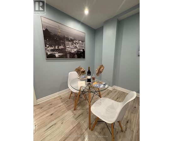 A dining room with a table set for two and a framed black and white photo on the wall.