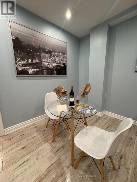A dining room with a table set for two and a framed black and white photo on the wall.