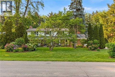 A house with a green lawn and trees in front.
