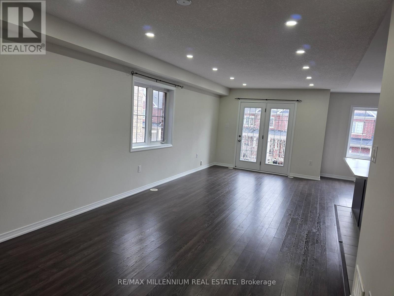 A spacious room with wood flooring and large windows.