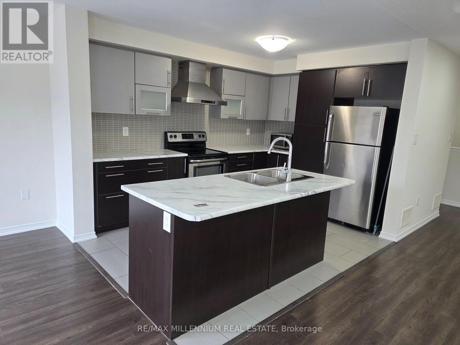 A kitchen with a white counter top and dark wood floors.