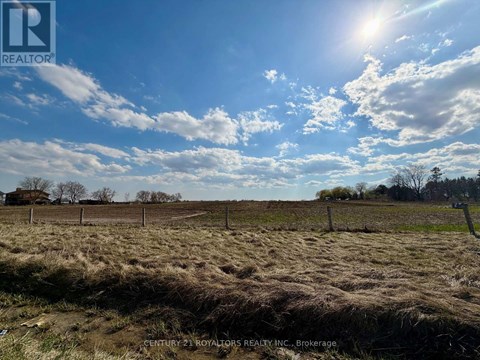 A field with a fence and a cloudy sky.
