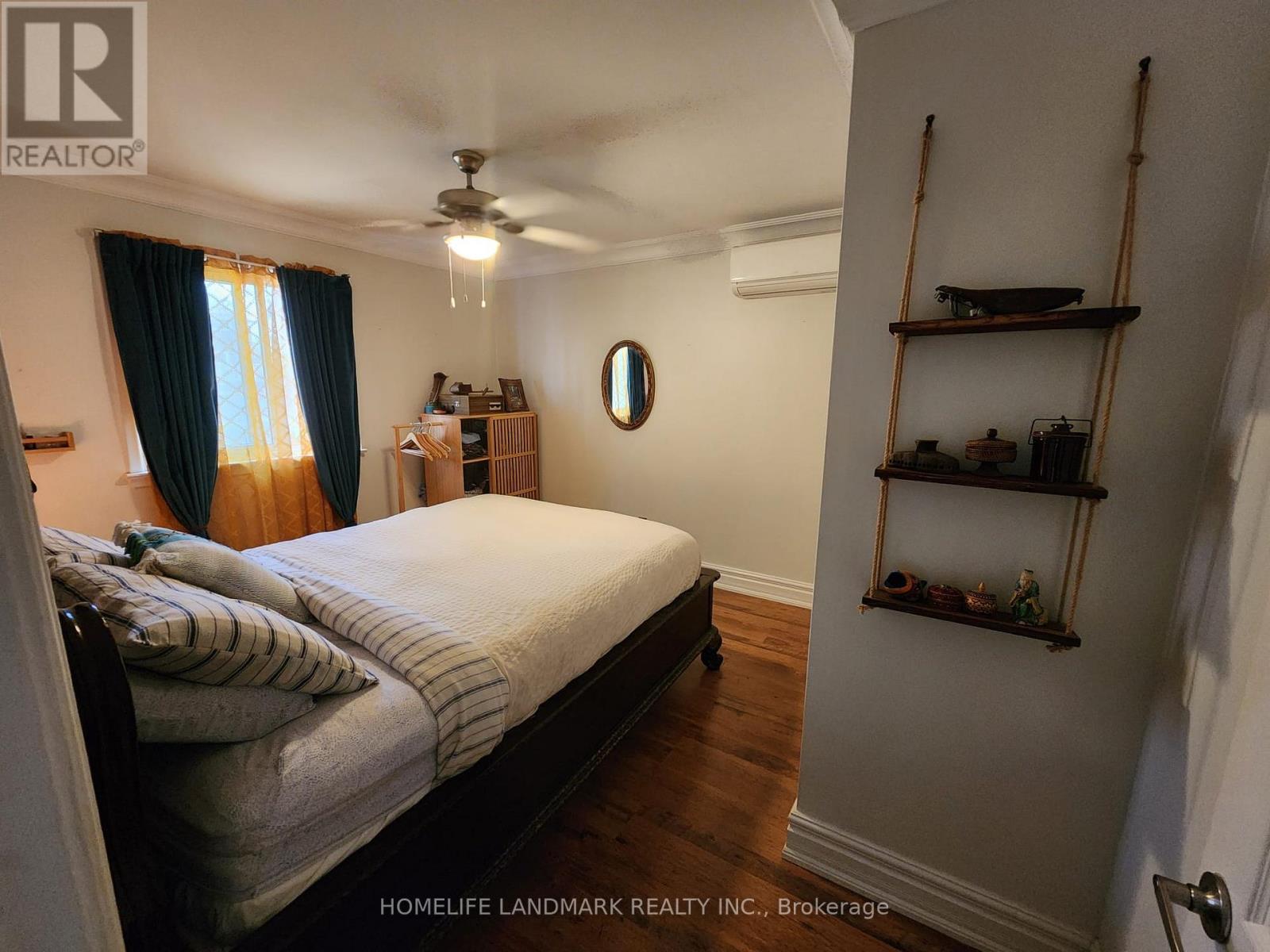 A bedroom with a bed, a ceiling fan, and a shelf with decorative items.