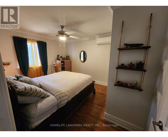 A bedroom with a bed, a ceiling fan, and a shelf with decorative items.