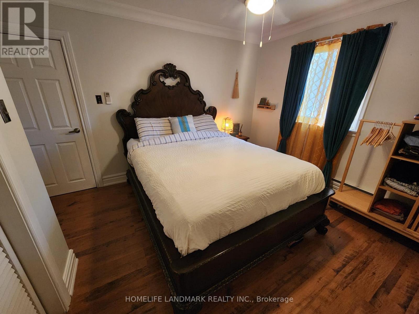 A bedroom with a large bed and a window with curtains.