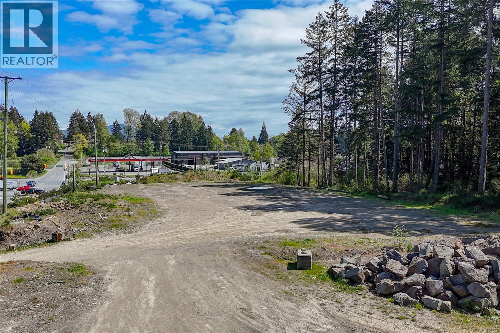 A dirt road leads to a building with a sign that says REALTOR.