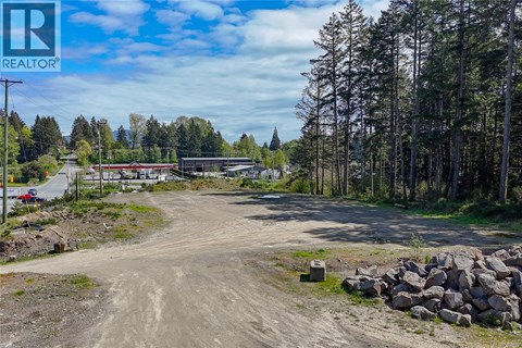 A dirt road leads to a building with a sign that says REALTOR.