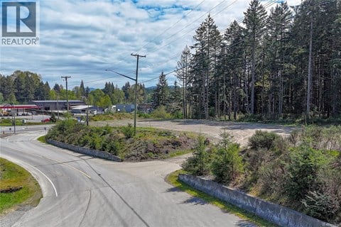 A road with a curve leading to a building with a sign that says REALTOR.