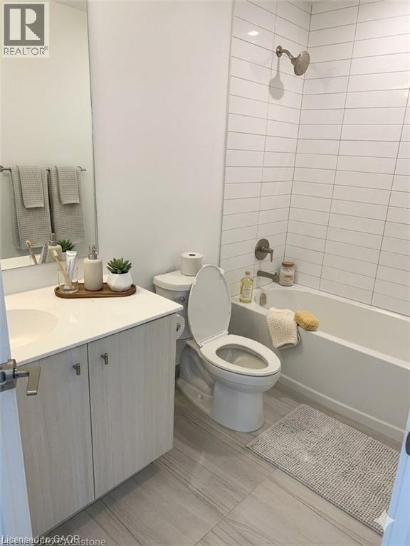 A white toilet in a bathroom with a white sink and a white bathtub.