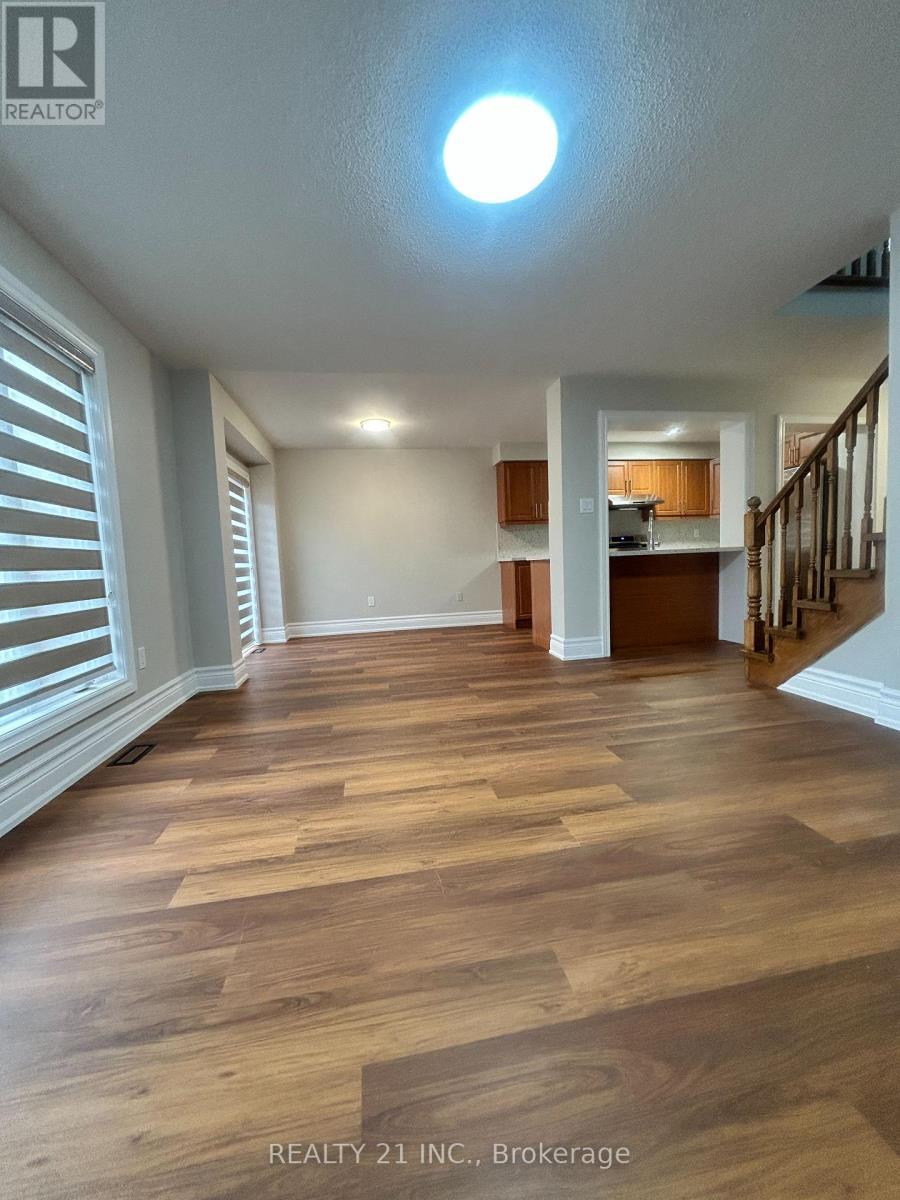 A spacious room with wooden flooring and a staircase leading to another room.
