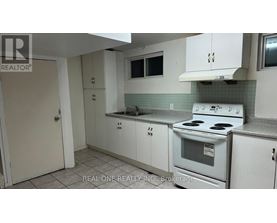 A white kitchen with a stove, sink, and cabinets.