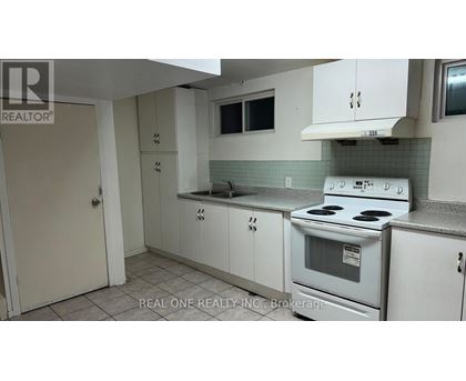 A white kitchen with a stove, sink, and cabinets.