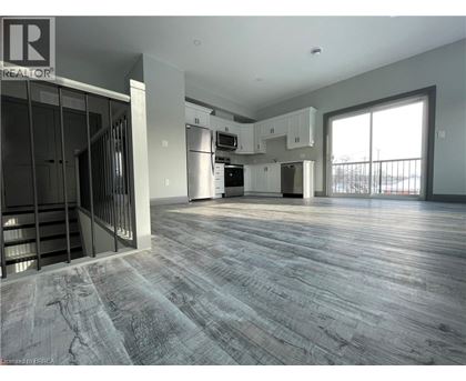 A spacious, empty room with wood flooring and a large window.