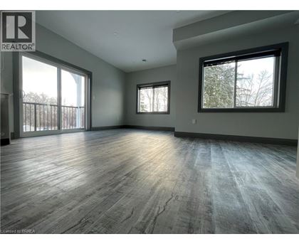A spacious room with wooden flooring and large windows.