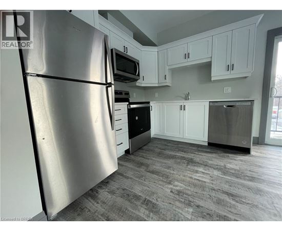 A kitchen with a refrigerator, microwave, oven, and dishwasher.