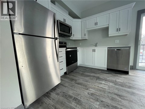 A kitchen with a refrigerator, microwave, oven, and dishwasher.