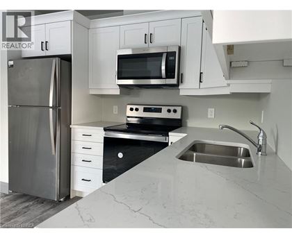 A kitchen with a refrigerator, microwave, oven, and sink.