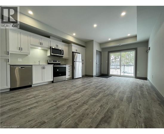 A spacious kitchen with stainless steel appliances and wooden flooring.