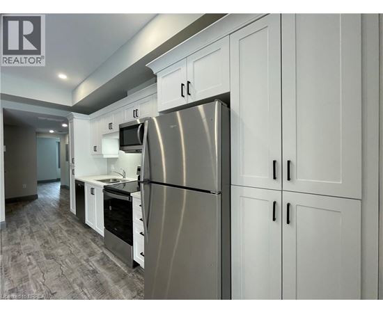 A modern kitchen with a stainless steel refrigerator and white cabinets.