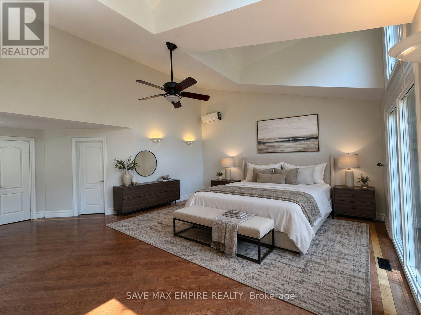 A bedroom with a large bed, a ceiling fan, and a painting on the wall.