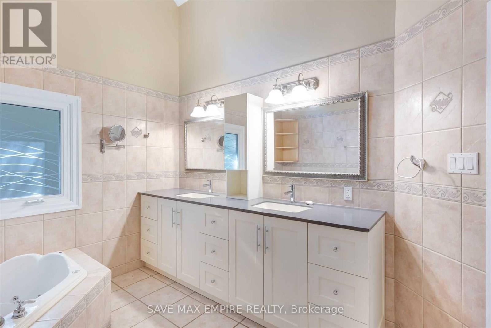 A bathroom with a tub, sink, and mirror.