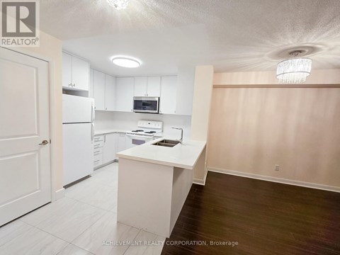 A kitchen with white cabinets and appliances in a real estate listing.