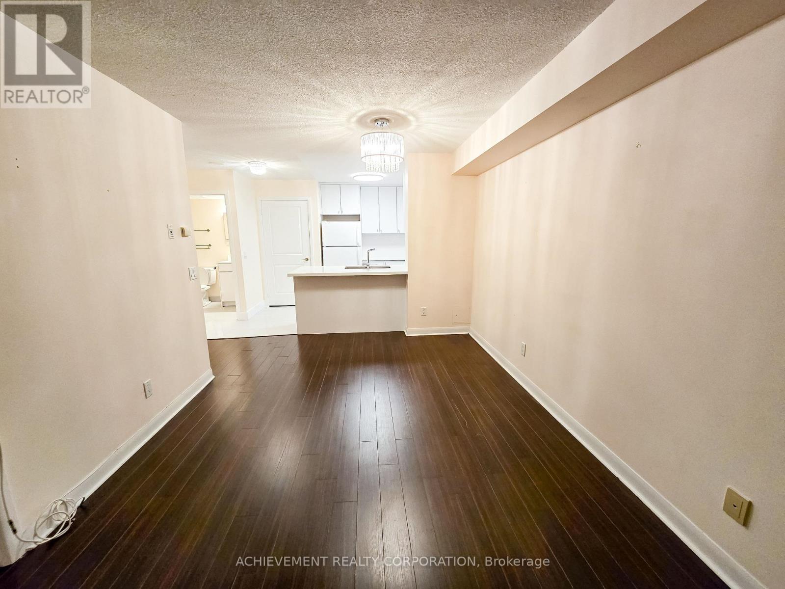 A room with wooden floors and white walls, with a light fixture on the ceiling.