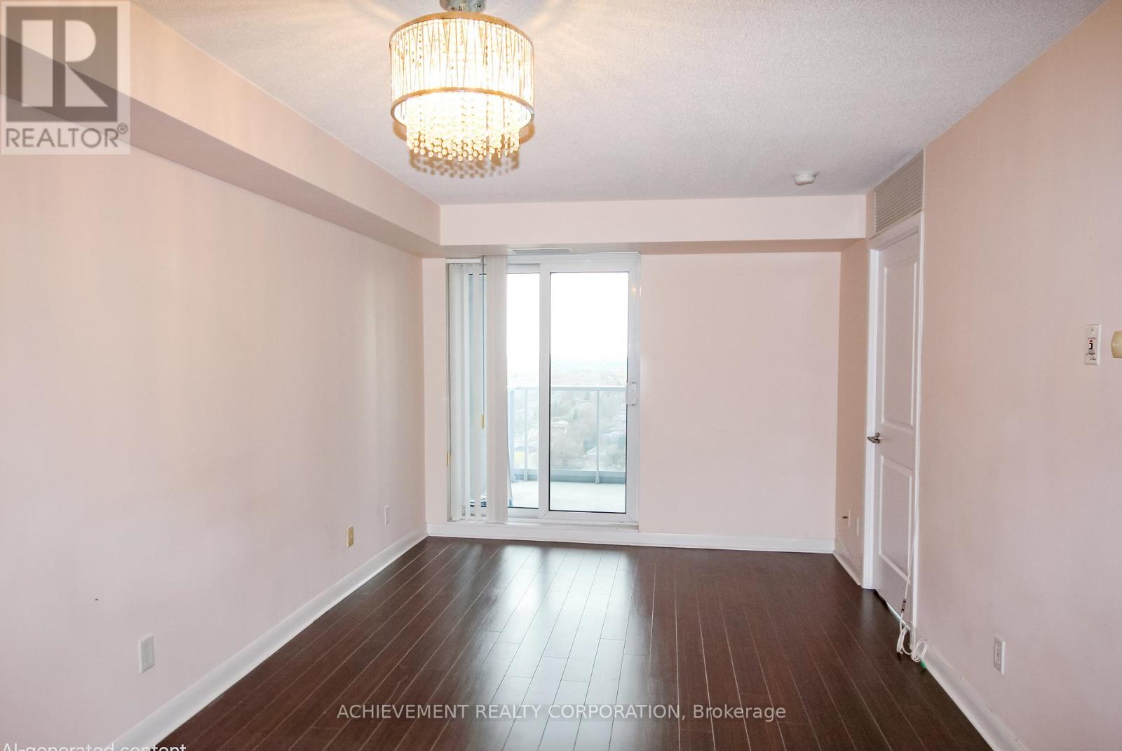 A large empty room with a chandelier and a sliding glass door.