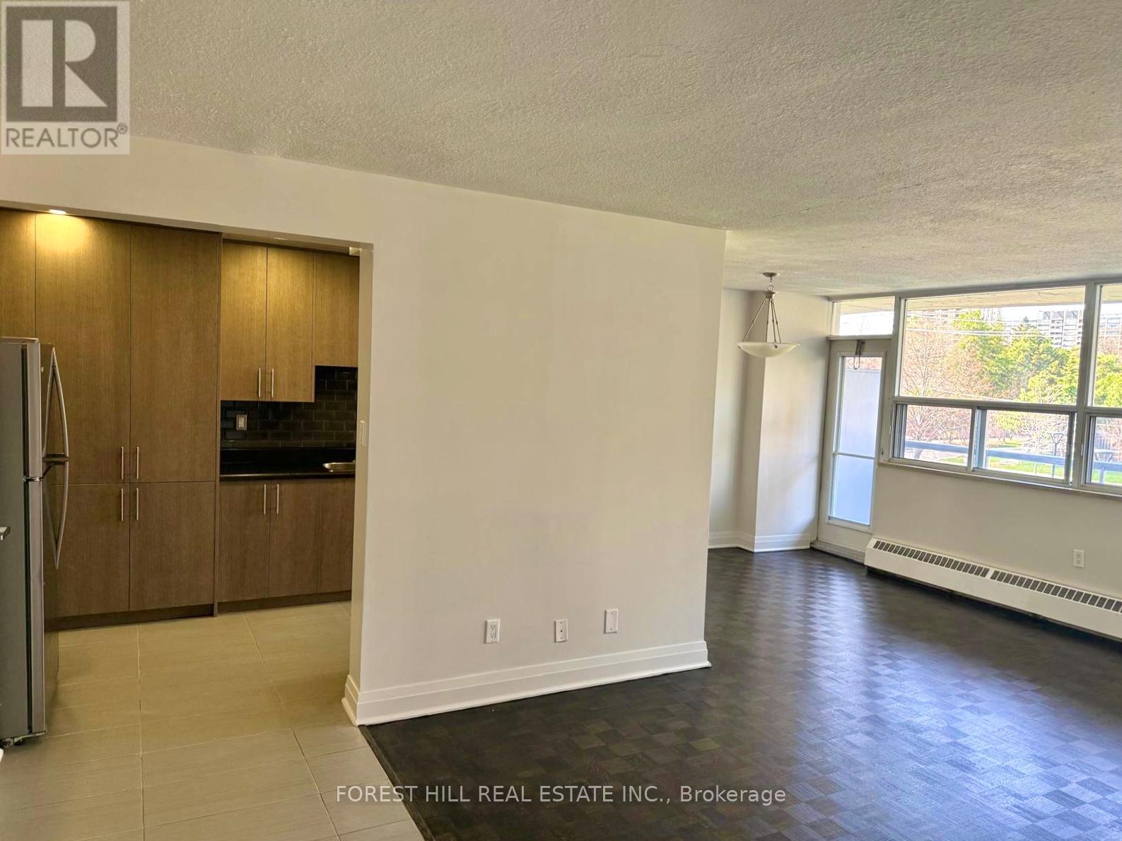 A spacious room with a kitchenette and a refrigerator.