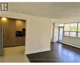 A spacious room with a kitchenette and a refrigerator.