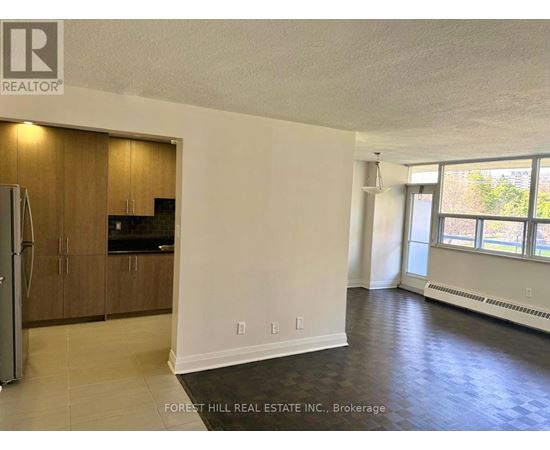 A spacious room with a kitchenette and a refrigerator.