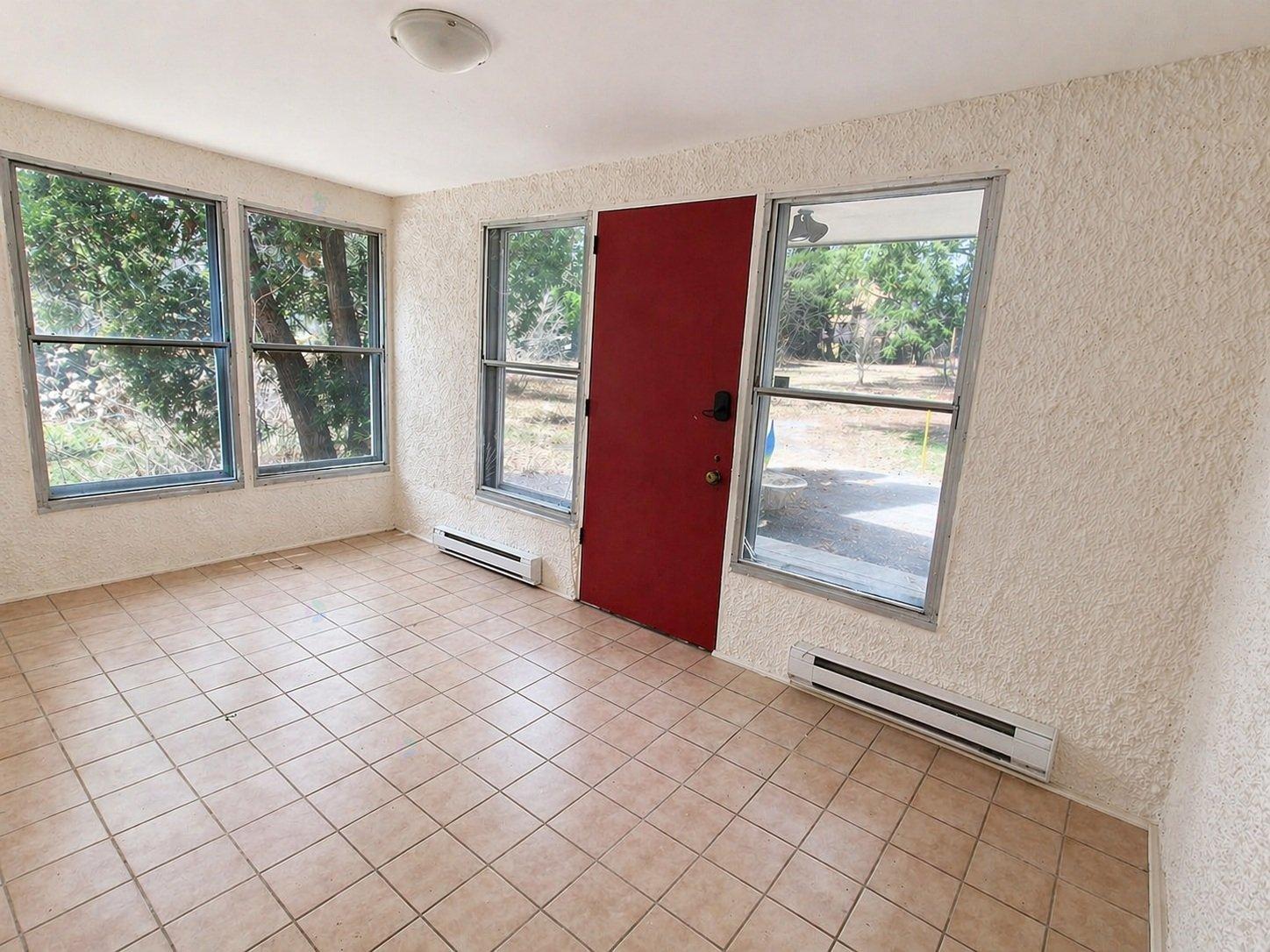 A room with a red door and tiled floor.