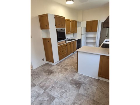 A kitchen with wooden cabinets and a tiled floor.