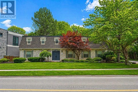 A house with a green lawn and trees in front of it.