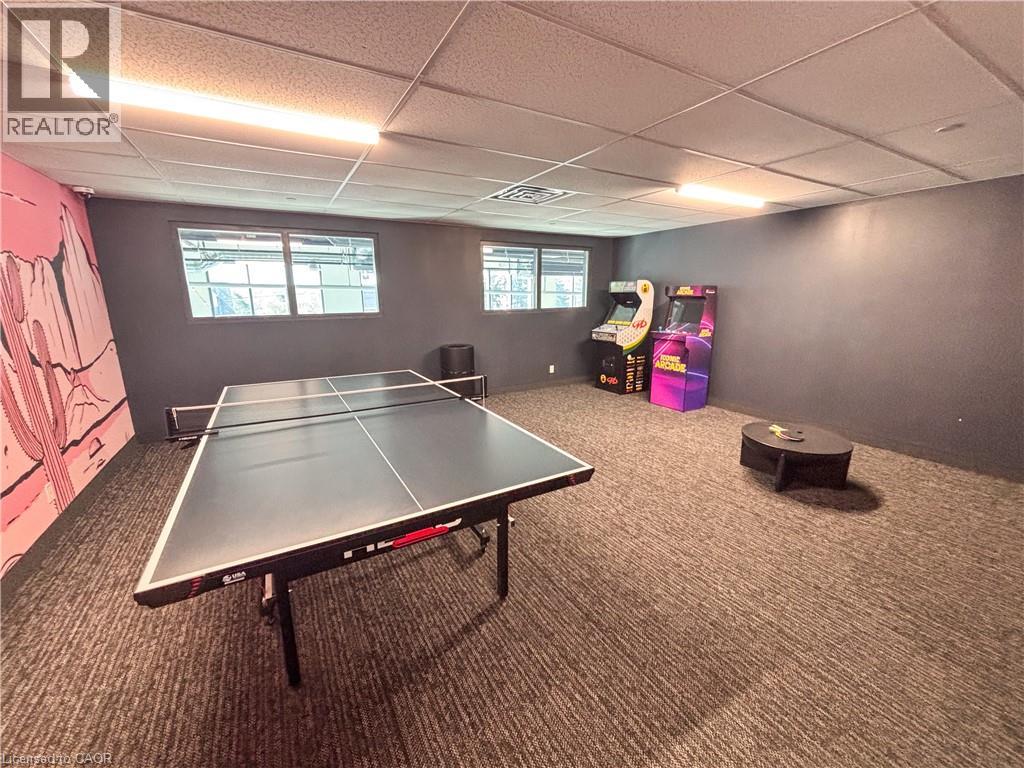 A ping pong table is in the middle of a room with a realtor logo on the wall.