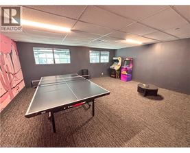 A ping pong table is in the middle of a room with a realtor logo on the wall.