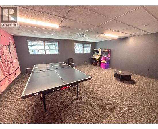 A ping pong table is in the middle of a room with a realtor logo on the wall.