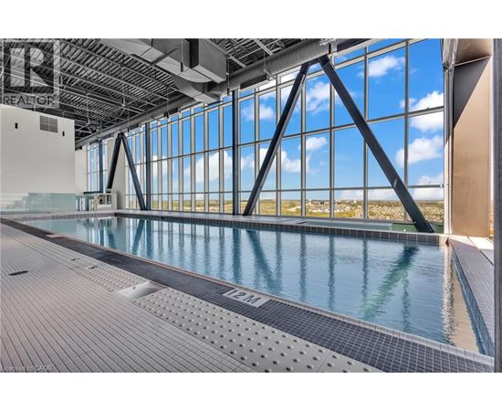 A large indoor swimming pool with a view of the sky through the windows.