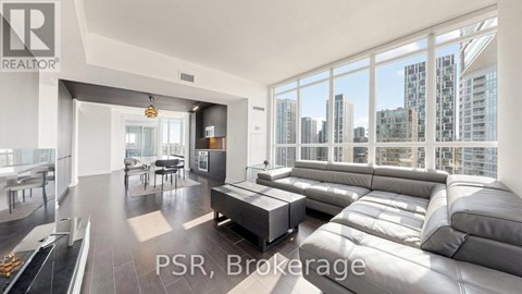 A modern living room with a large grey sofa and a view of the city.
