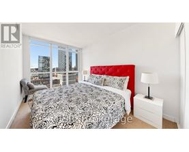 A bedroom with a large bed and a city view through the window.