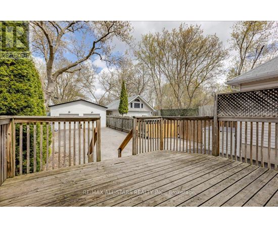 A wooden deck with a railing and a tree in the background.